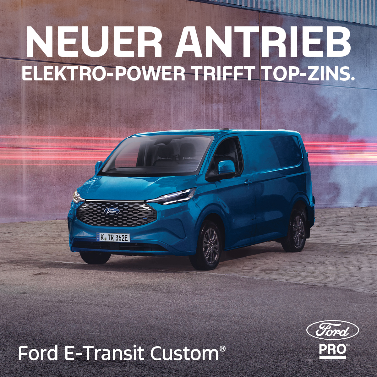 Zu sehen ist ein blauer Ford E-Transit Custom vor einem rosa Hintergrund