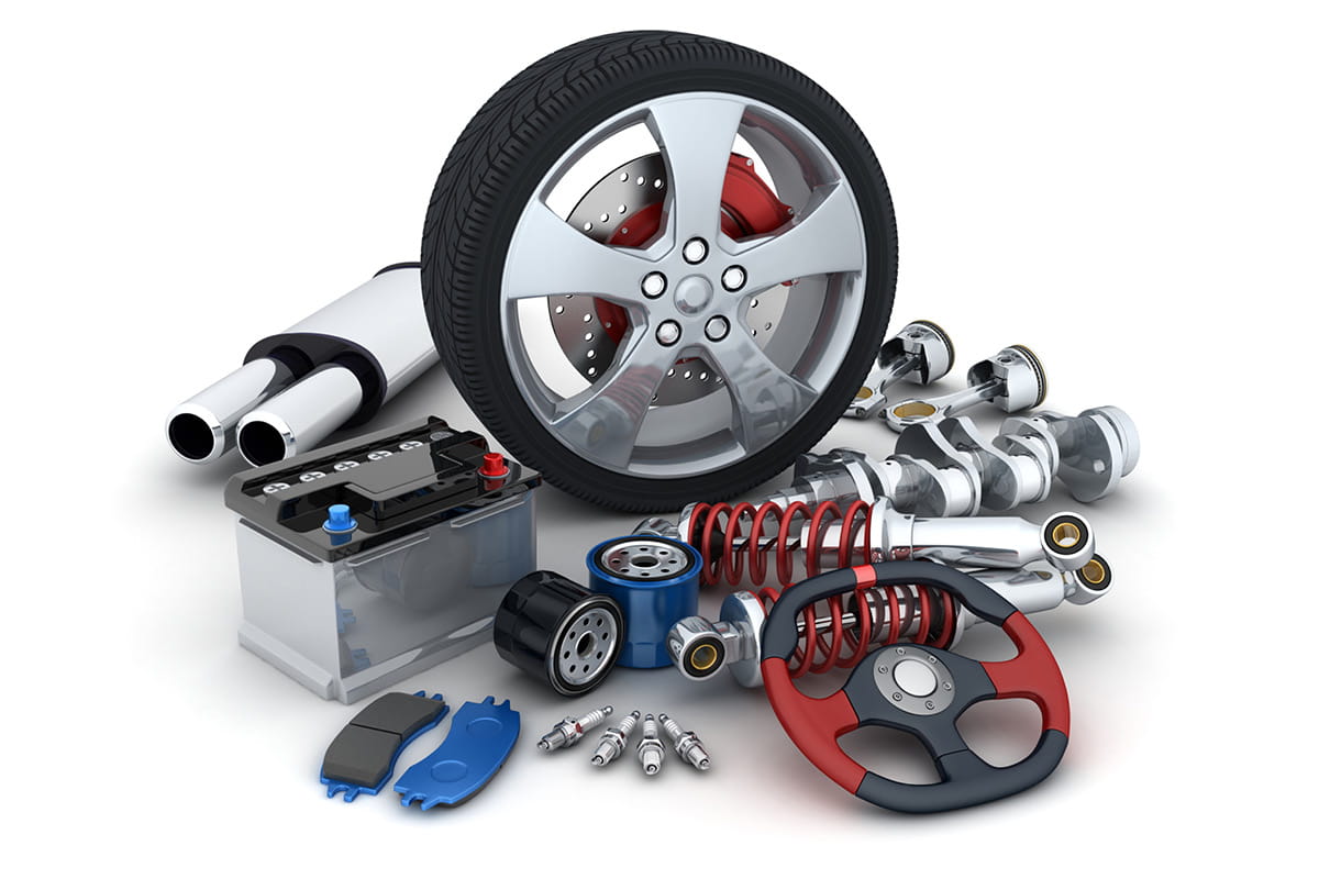 zu sehen sind verschiedene Autoteile wie Lenkrad, Bremsscheibe, Stoßdämpfer, Zahnräder, Kolben, Reifen, Zündkerzen, Ölfilter, Benzinkanister und Motorbehälter die auf einer weißen Oberfläche verteilt liegen.